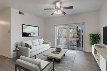 A living room with a grey couch, a coffee table, and a ceiling fan.
